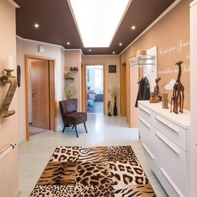 Afrikanisch inspirierter Flur mit Tiermuster-Teppich, Holzmöbeln und Dekoration.