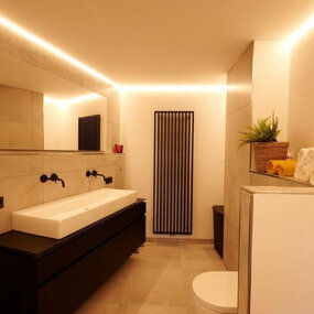 Modernes Badezimmer mit großem Spiegel, Waschbecken, LED-Beleuchtung und Handtüchern.