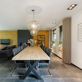 Modernes Esszimmer mit großem Holztisch, schwarzen Stühlen und stilvoller Dekoration.