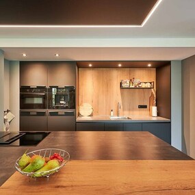 Moderne offene Küche mit Holzarbeitsplatte, integriertem Herd und stilvollen Einbaugeräten.